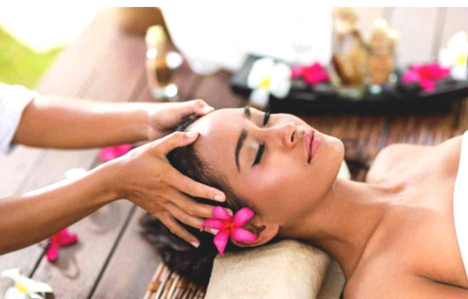 Image d'un massage hawaïen sur la tête d'une femme portant une fleur à l'oreille
