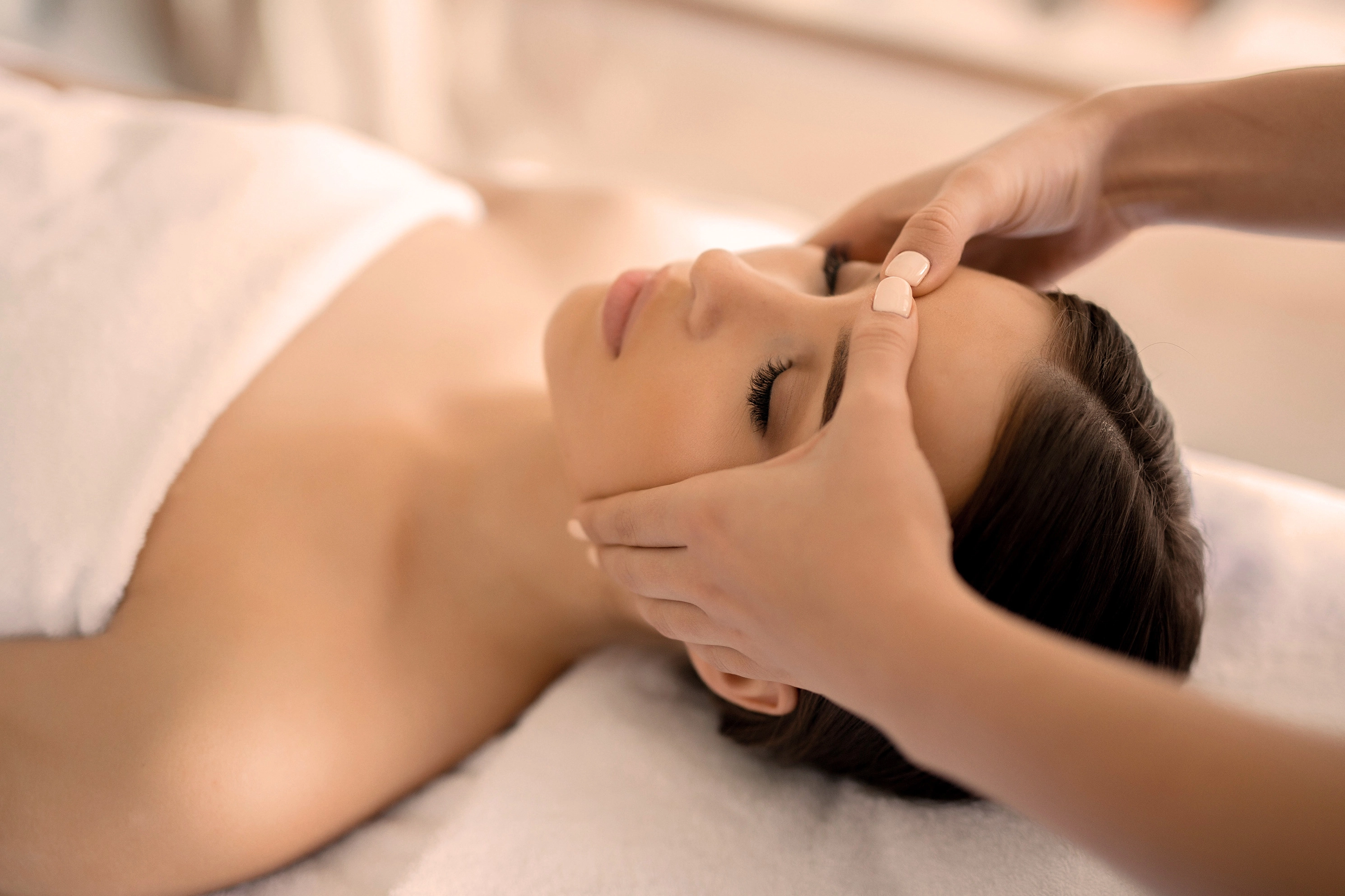 Image d'un massage kobido sur la tête d'une femme portant une fleur à l'oreille